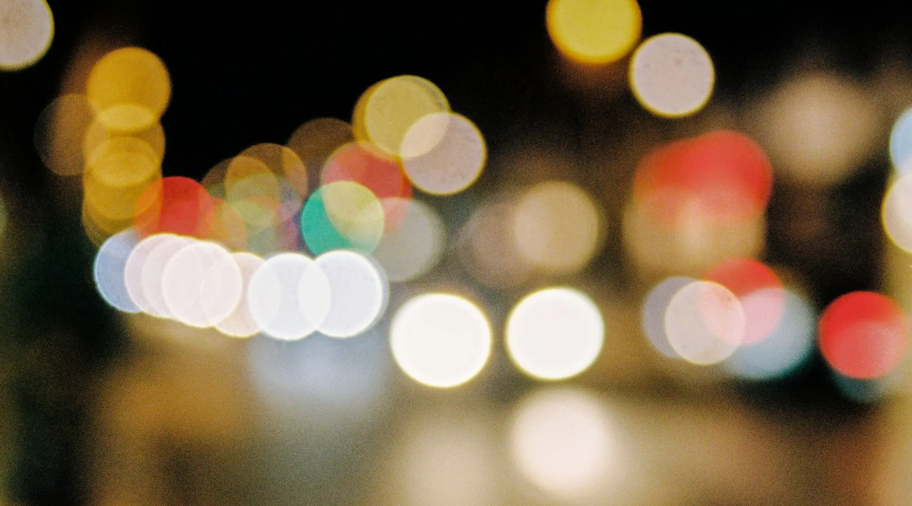 Blurred gold and amber bokeh lights on a Sydney street at night, evoking the city's event and nightlife scene.