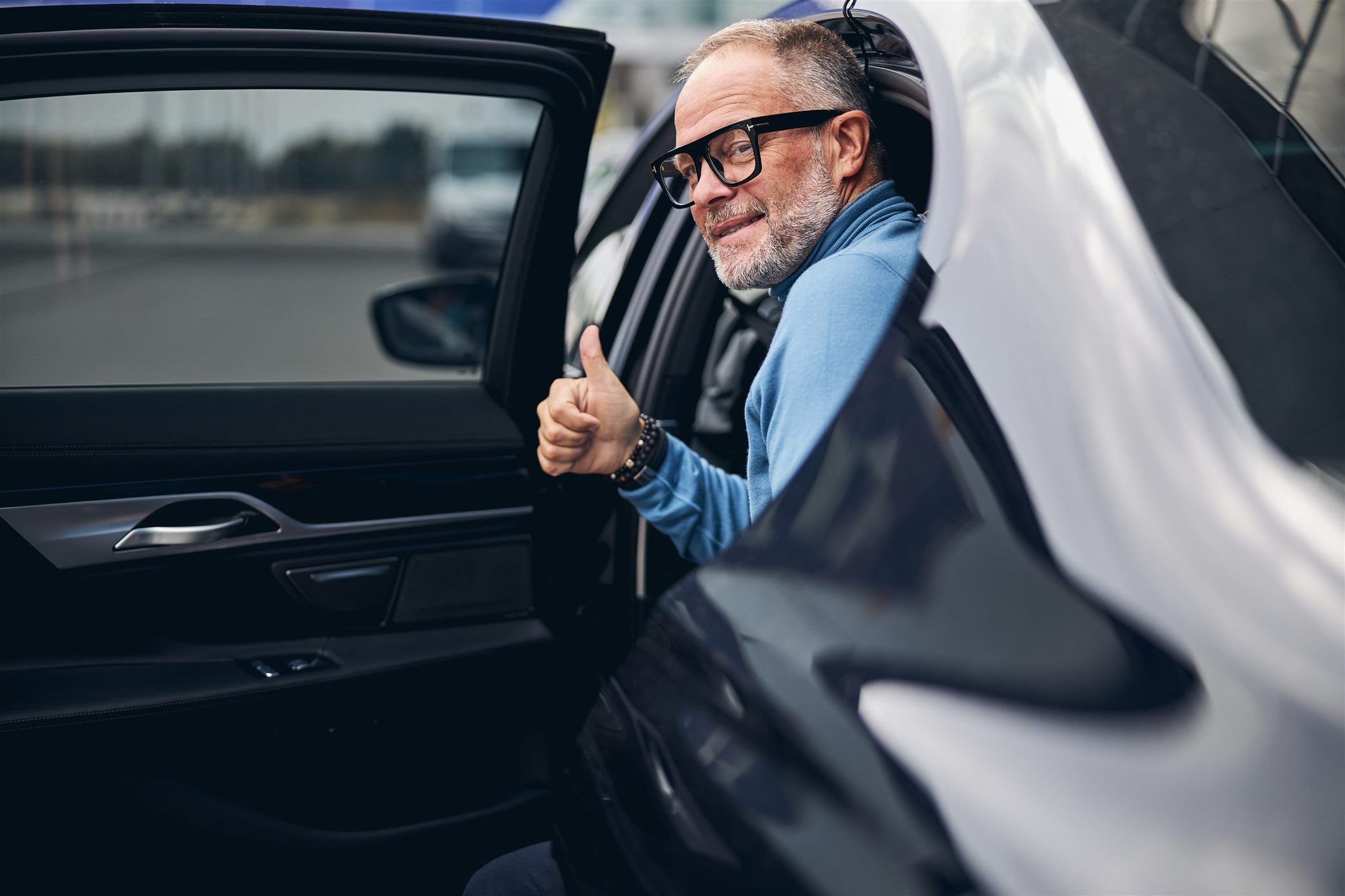 A satisfied passenger giving a thumbs up as he steps out of a Captain Taxis vehicle