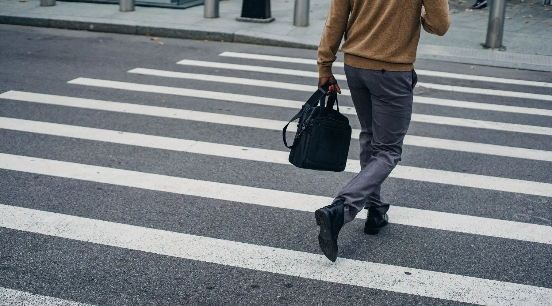 A business professional with a briefcase crossing a city street